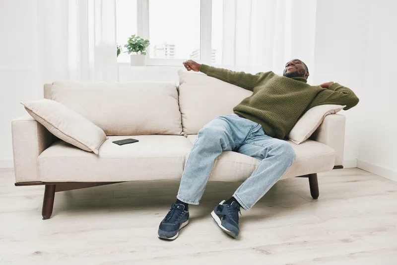 Relaxed man enjoying comfort on a light sofa in a cozy living room, showcasing casual wear and a serene mood with soft natural light