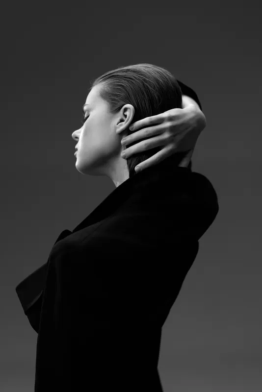 Black and white portrait of a thoughtful woman with slicked-back hair in minimalist style