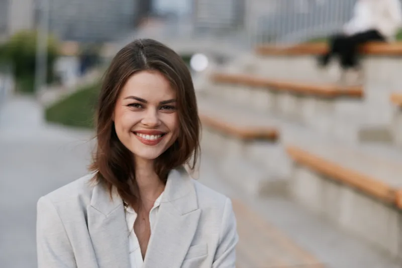 smiling woman in business jacket outdoors urban background confident emotion autumn season