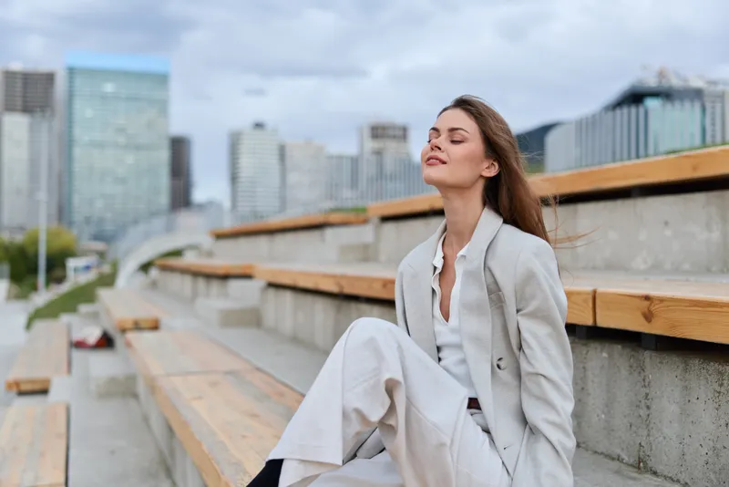 Confident woman in stylish suit enjoying urban scenery with a relaxed expression, embodying business empowerment and modern professionalism.