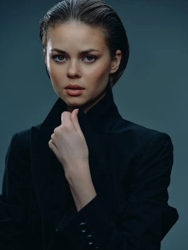 serious woman wearing black suit in studio with moody lighting and dark background
