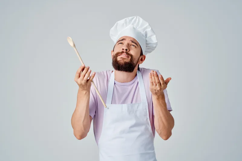 Бородатый мужчина-шеф-повар в фартуках работает на ресторанной кухне, создавая изысканные блюда
