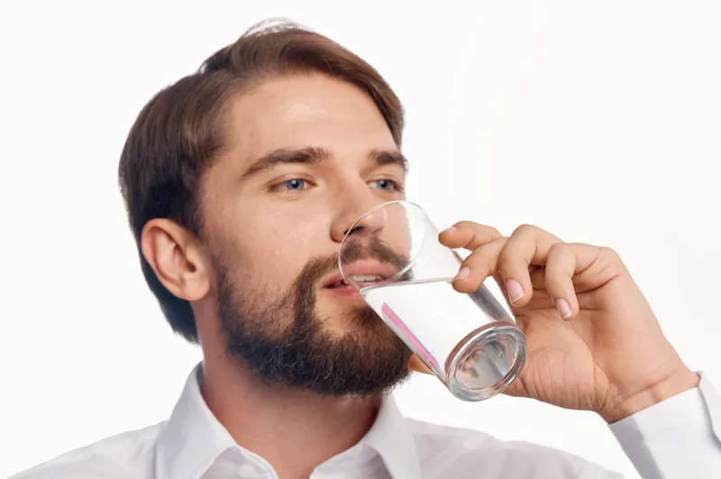 Красивый мужчина заботится о здоровье, чистая вода, светлый фон