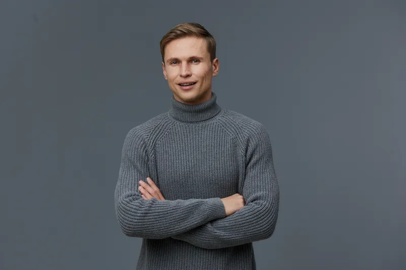 smiling young caucasian man in gray sweater stand pose crossed arms look camera isolated on gray background casual wear digital detox relaxation concept