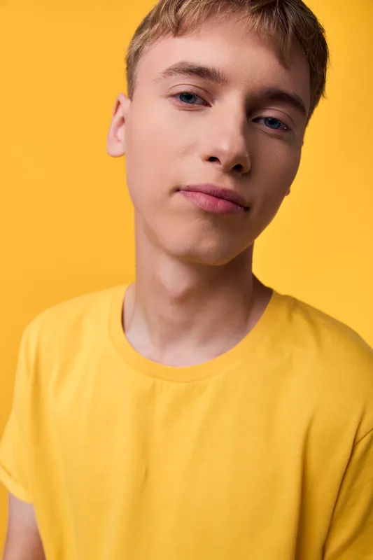 Man in a bright yellow shirt, close up studio headshot showcasing casual fashion with a confident youth look against a vivid backdrop, with vibrant mood
