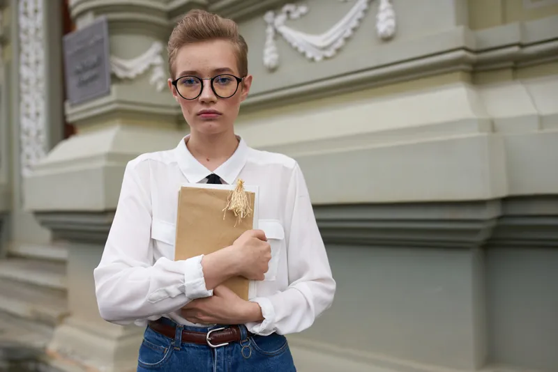 Коротко стриженная женщина с книгой в руках на открытом воздухе, читает, образование