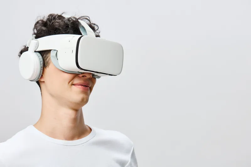 Молодой человек в VR-шлеме и наушниках улыбается, погружённый в виртуальную реальность