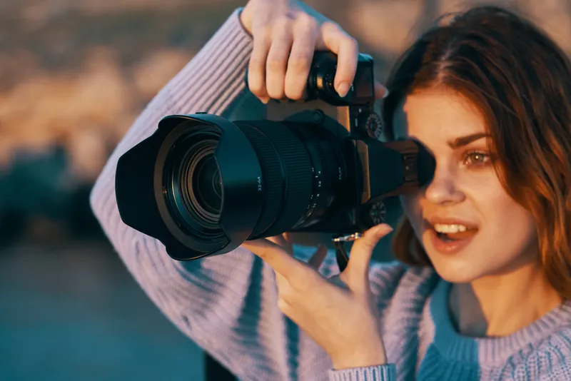 Красивая женщина-фотограф на природе в горах фотографирует модель на фоне пейзажа