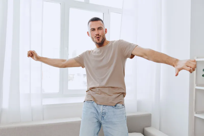 A joyful man expressing freedom and relief in a light-filled space, embracing digital detox and emotional minimalism in his everyday life.
