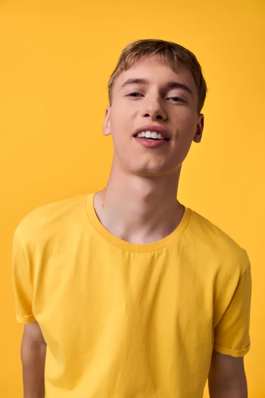 Young man, yellow shirt, bright background, casual fashion, smiling, studio model, contemporary style, everyday wear in a clean sunny setup for lifestyle and ecommerce visuals