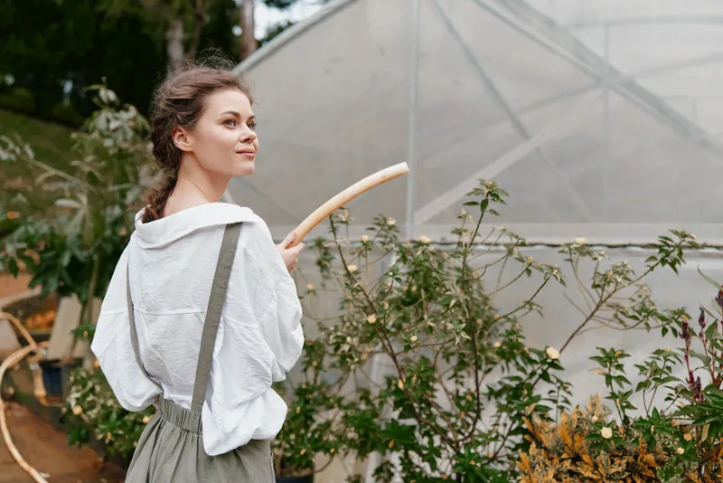 Young woman gardening in a greenhouse, dressed in casual clothes, showcasing joy and serenity amidst lush greenery and soft colors