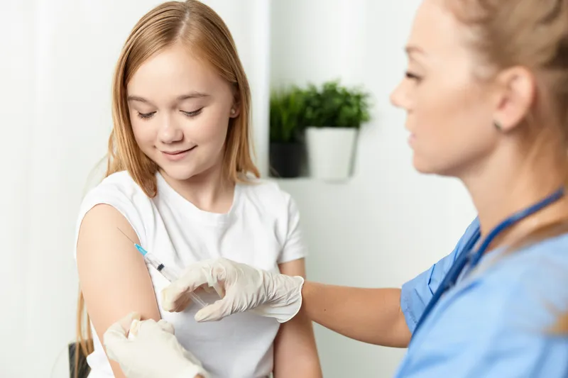 Женщина-врач делает девочке укол в руку — вакцинация