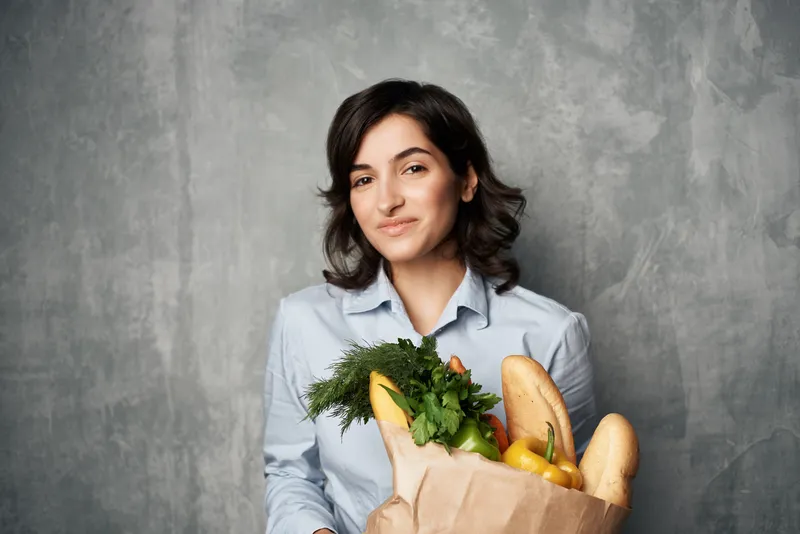 Весёлая брюнетка с пакетом продуктов, доставка покупок