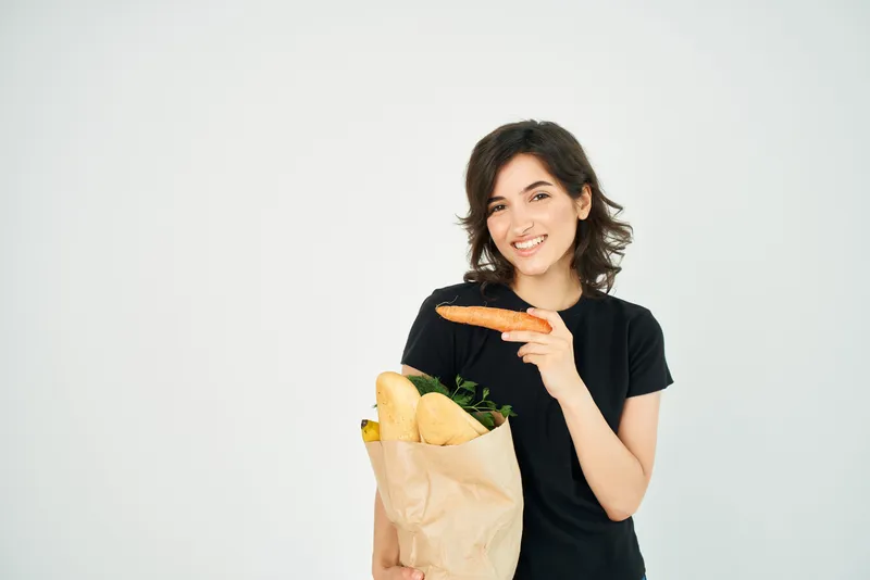 Весёлая брюнетка с пакетом продуктов, доставка здоровой еды, супермаркет