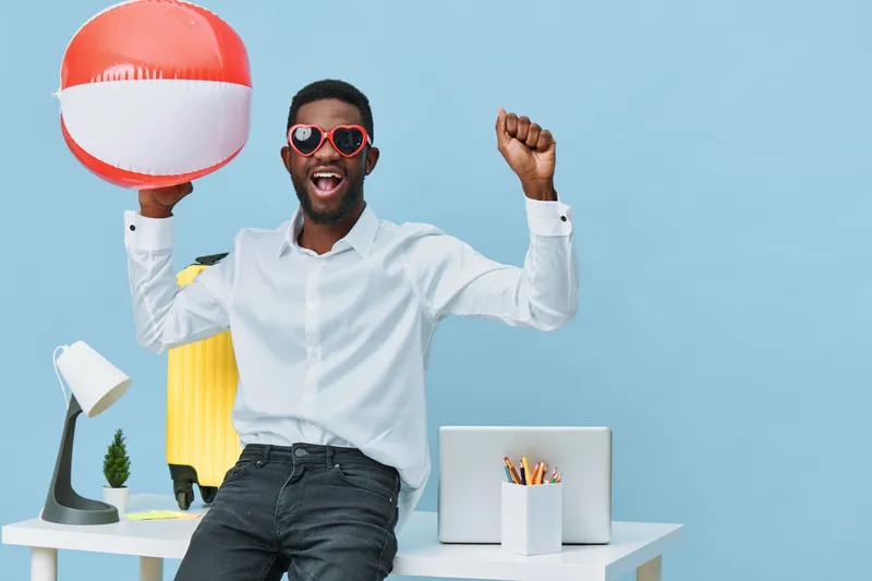 Happy cheerful man with dark skin, sunglasses, white shirt, black pants, joy, celebration, summer, beach ball, casual style, vibrant colors, studio shot, isolated on blue background. People lifestyle 