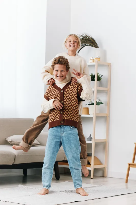 Authentic scene shows children at home engaged in playful activity, capturing school themed lifestyle and genuine fun. Soft light, cozy space, and open smiles highlight everyday joy and natural style.