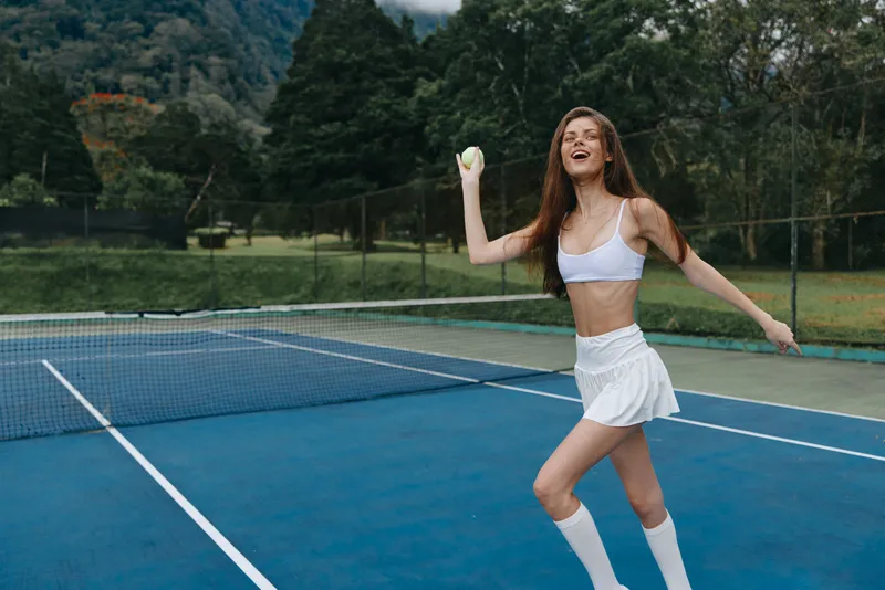 Active young woman enjoying a game of tennis on a sunny day, wearing a sporty outfit with a joyful expression, showcasing healthy lifestyle and outdoor sports