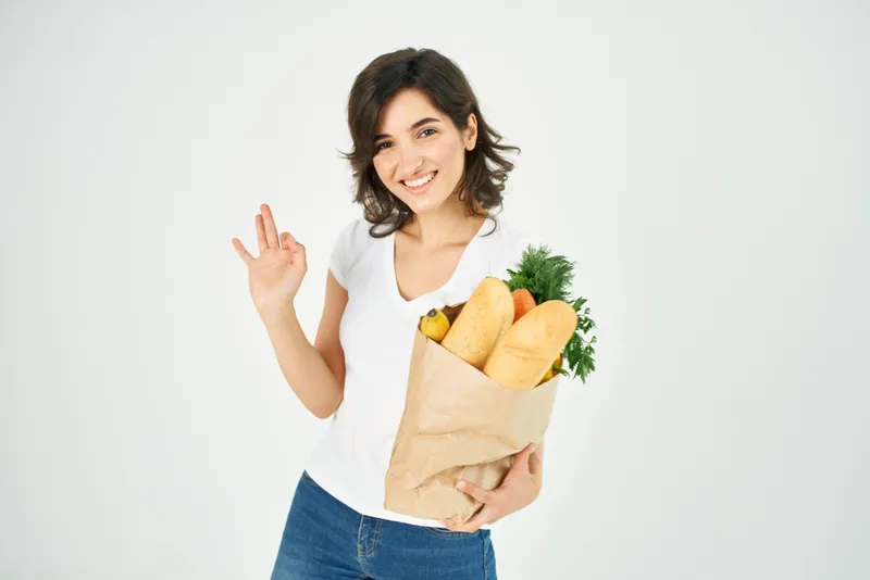 Женщина с пакетом продуктов, совершающая покупки овощей для доставки