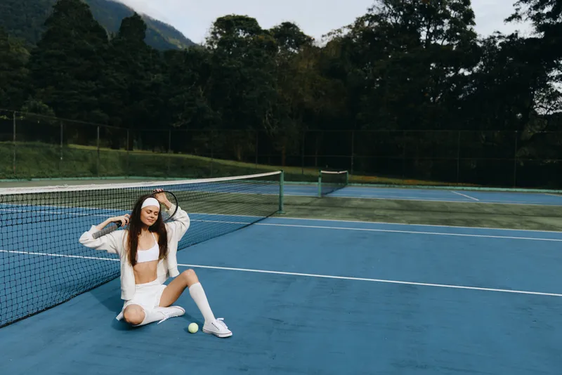 Young athletic woman in sporty white outfit showing joy on outdoor tennis court, vibrant colors, captured during summer, represents active lifestyle