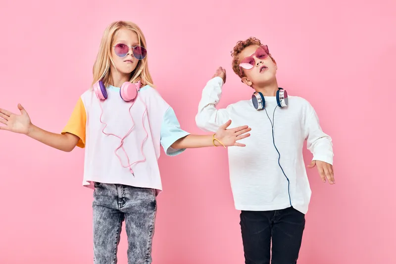 Очаровательные маленькие дети со светлыми волосами в модных очках слушают музыку