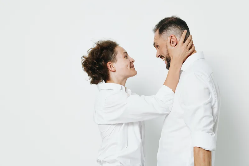 A professional man in a white shirt shares a warm moment with a colleague against a clean, isolated background, signaling confidence, teamwork, and positive energy in a business setting.