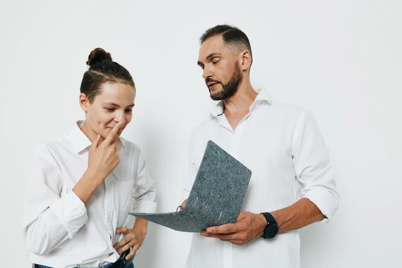 A business professional man stands with a colleague, focused and thoughtful, on an isolated colored background. The scene conveys emotion, teamwork, and professional intent.