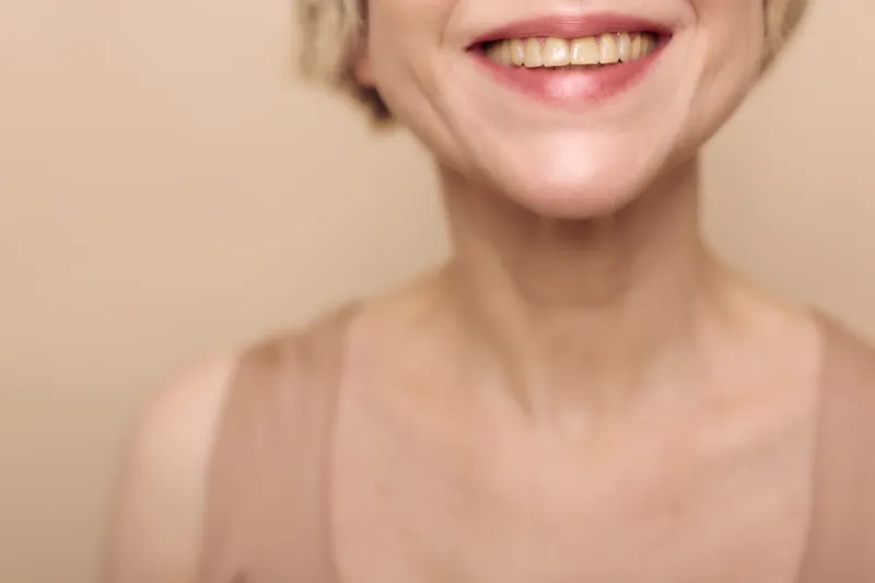 Closeup of smiling middle aged woman with natural skin and teeth showing. Concept for happiness, aging, beauty, wellness, positive emotions, and healthy lifestyle.