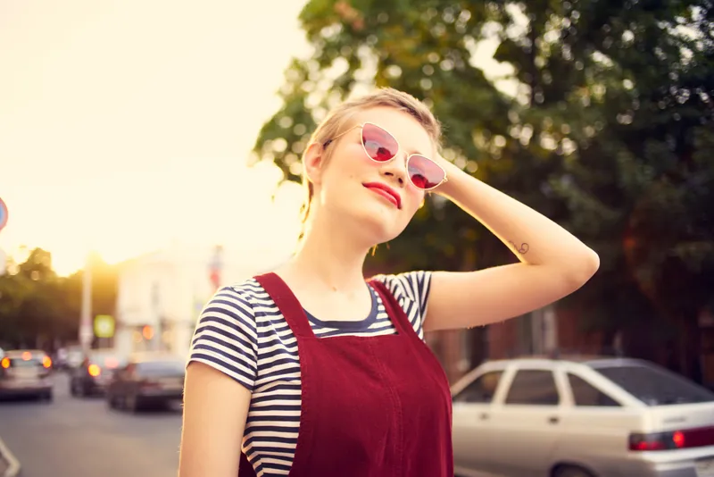 Женщина в солнцезащитных очках позирует на открытом воздухе, демонстрируя летний модный образ