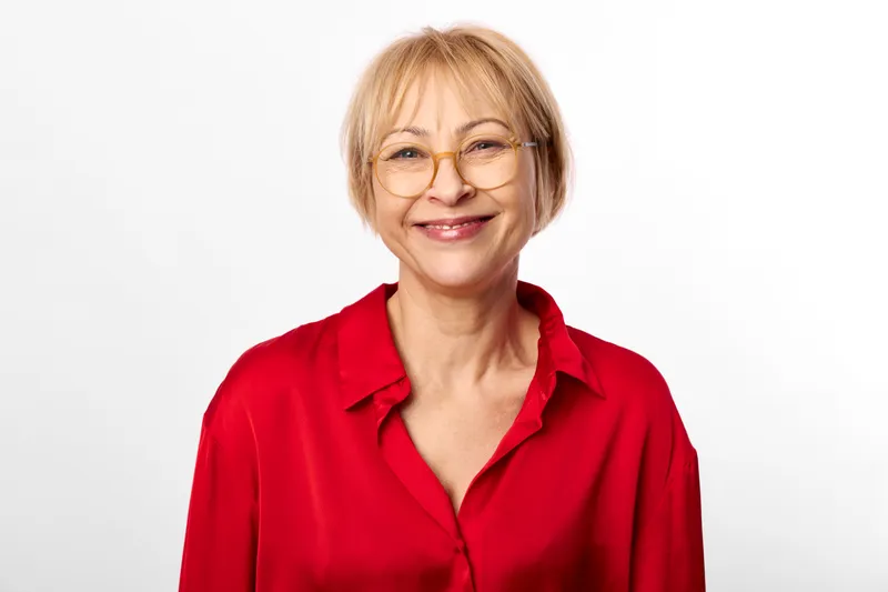 Portrait of an elderly woman, smiling gently in a red shirt against a white studio background, isolated and relaxed, concept of healthy aging and warmth, friendly look