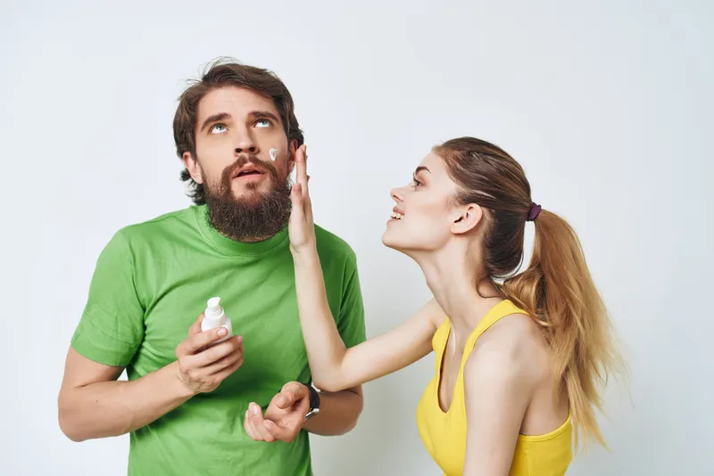 Молодая пара в разноцветных футболках занимается уходом за собой в ванной комнате