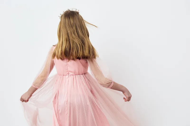 A girl in a pink tulle dress twirling, showcasing joy and innocence against a clean white background, perfect for children s fashion and childhood themes
