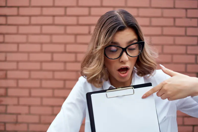 Деловая женщина-менеджер в очках работает с документами на фоне кирпичной стены