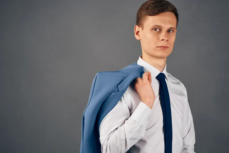 Бизнесмен в рубашке с галстуком, пиджак на плече, излучает уверенность в себе в офисе
