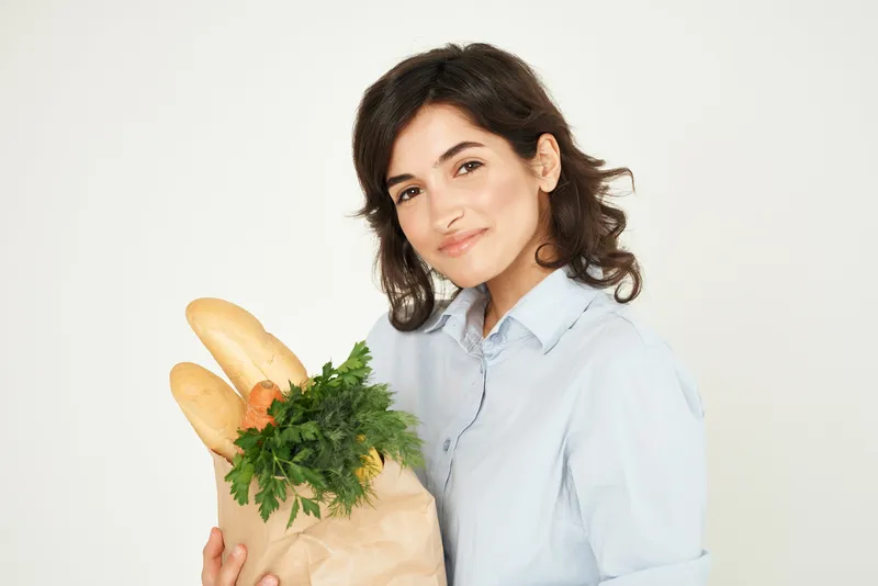 Брюнетка держит продукты в супермаркете, домохозяйка совершает покупки