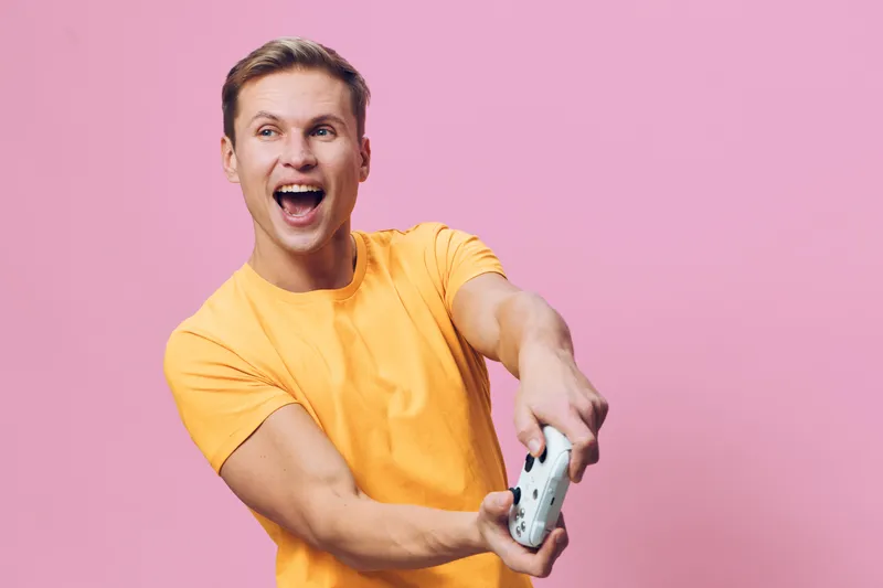 Joyful young man in bright yellow t-shirt taking selfie with smartphone on pink background studio portrait. Happy expression, cheerful mood, casual style, lifestyle concept, fun, excitement.
