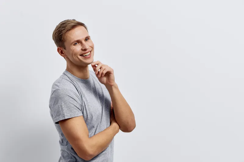 Smiling young caucasian man casual grey t-shirt looking aside thoughtful pose isolated on plain light grey background digital nomad concept