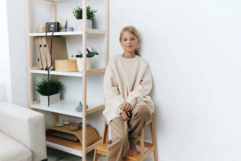 Authentic lifestyle photo of a calm child seated on a stool in a cozy study corner, hinting at school routines and mindful play in a simple home setting.