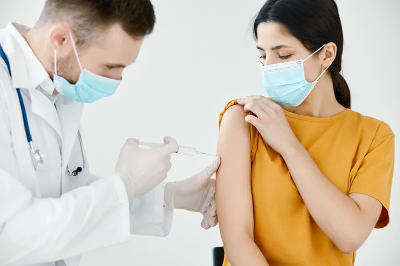 Врач в медицинской маске делает инъекцию в плечо женщины, вакцинация, укол, здоровье