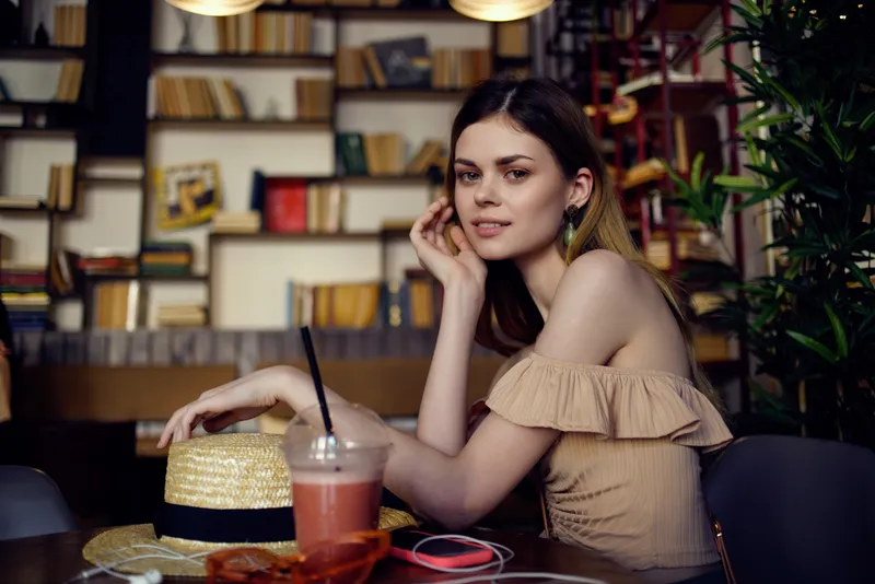 Красивая женщина с книгой в руках в кафе, стильная одежда