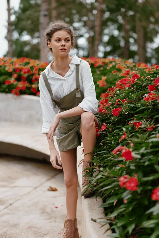 Young woman in nature wearing casual outfit with flowers in background, expressing tranquility and connection to nature, perfect for lifestyle and fashion themes