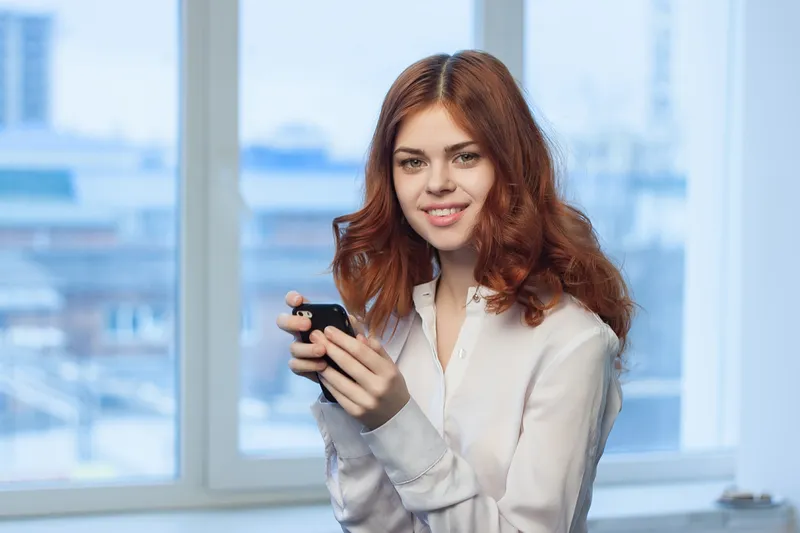Симпатичная женщина в рубашке с телефоном в руке, общение, офисный профессионал