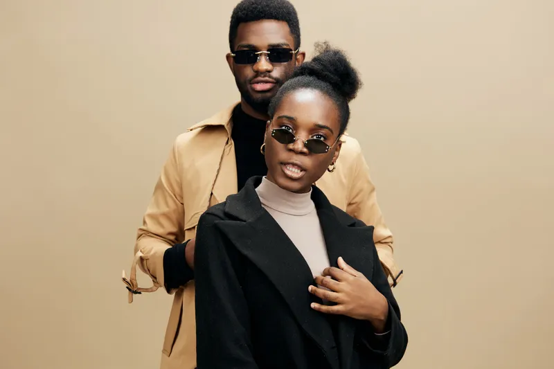Stylish African models posing in sunglasses, showcasing urban fashion and confidence, with a neutral background and warm colors, perfect for lifestyle content