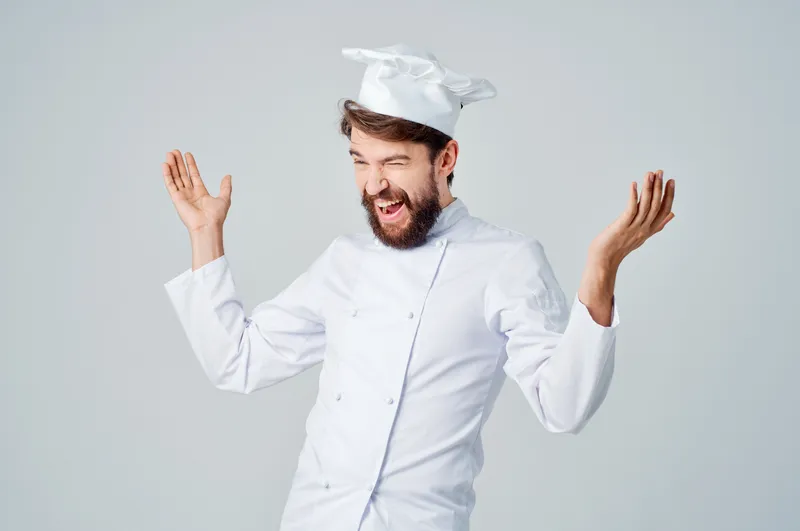 Повар-мужчина на кухне, жестикулирующий руками на светлом фоне