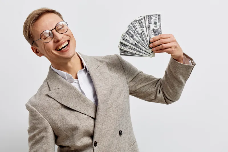 Smiling happy caucasian man holding cash money fan success expression studio portrait finance concept