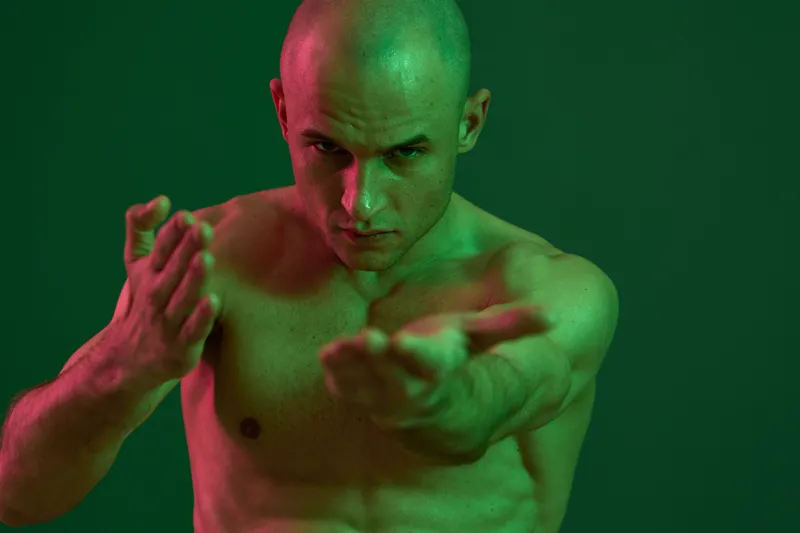 Athletic man showcasing martial arts skills in a striking pose. His muscular physique and focused expression reflect strength and determination.