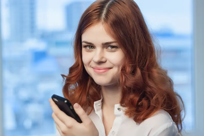 Женщина с телефоном в руках в офисе — технологии, профессионализм