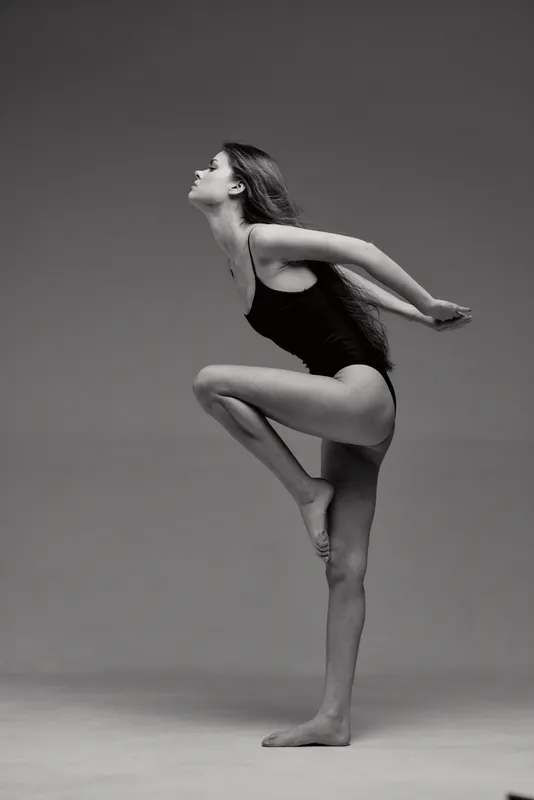 graceful woman dancing in black and white with flexible pose in studio lighting