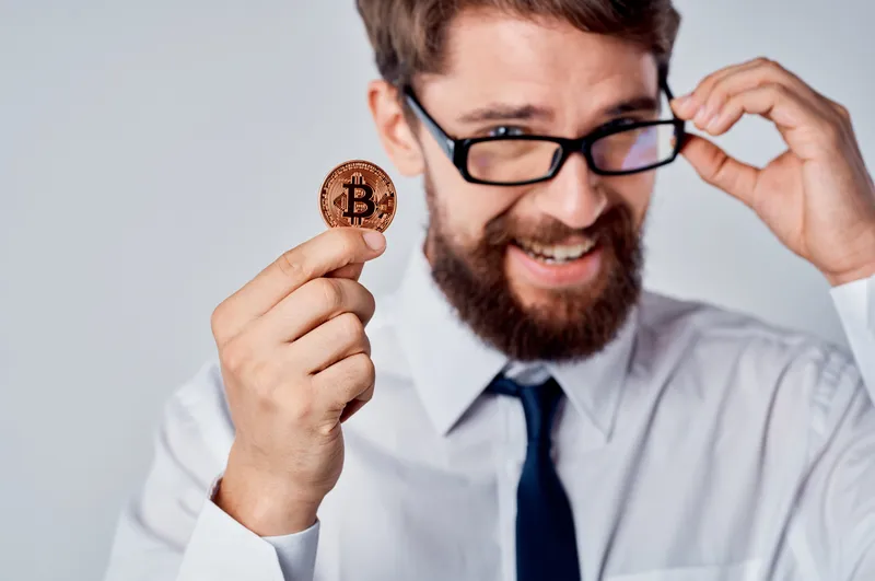 Весёлый мужчина с золотой монетой, биткоином и криптовалютой