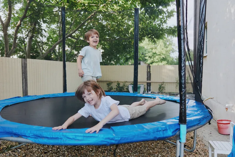 Joyful children playing on a trampoline, enjoying a sunny day outdoors with laughter and excitement, showcasing the essence of childhood fun.