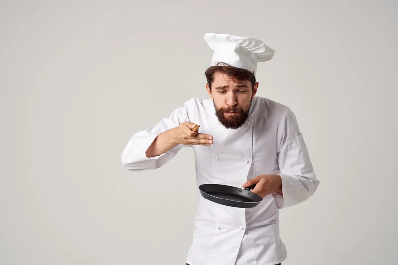 Повар работает с кухонной утварью на кухне ресторана